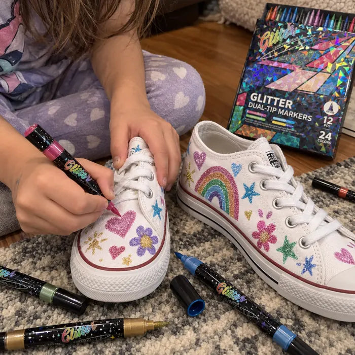 Child decorating white canvas shoes with glitter markers